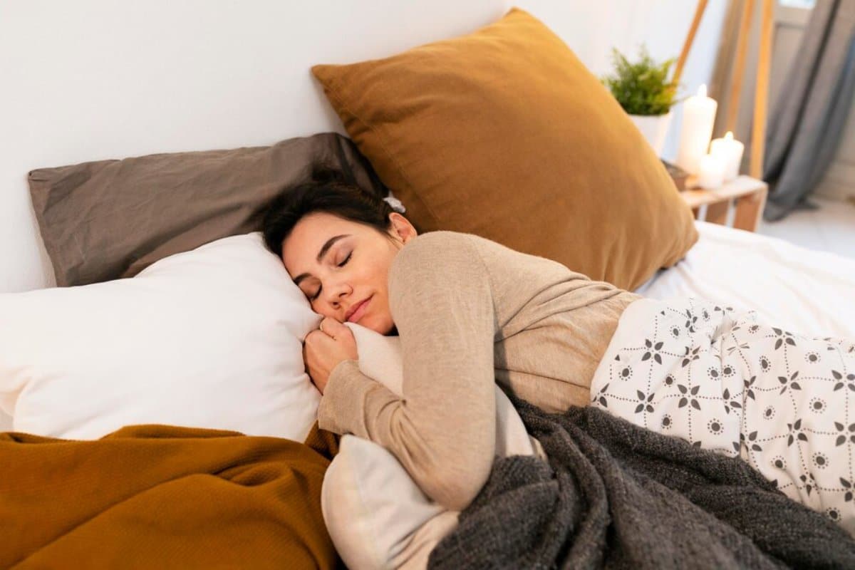 A woman peacefully sleeping in her warmly decorated bedroom.