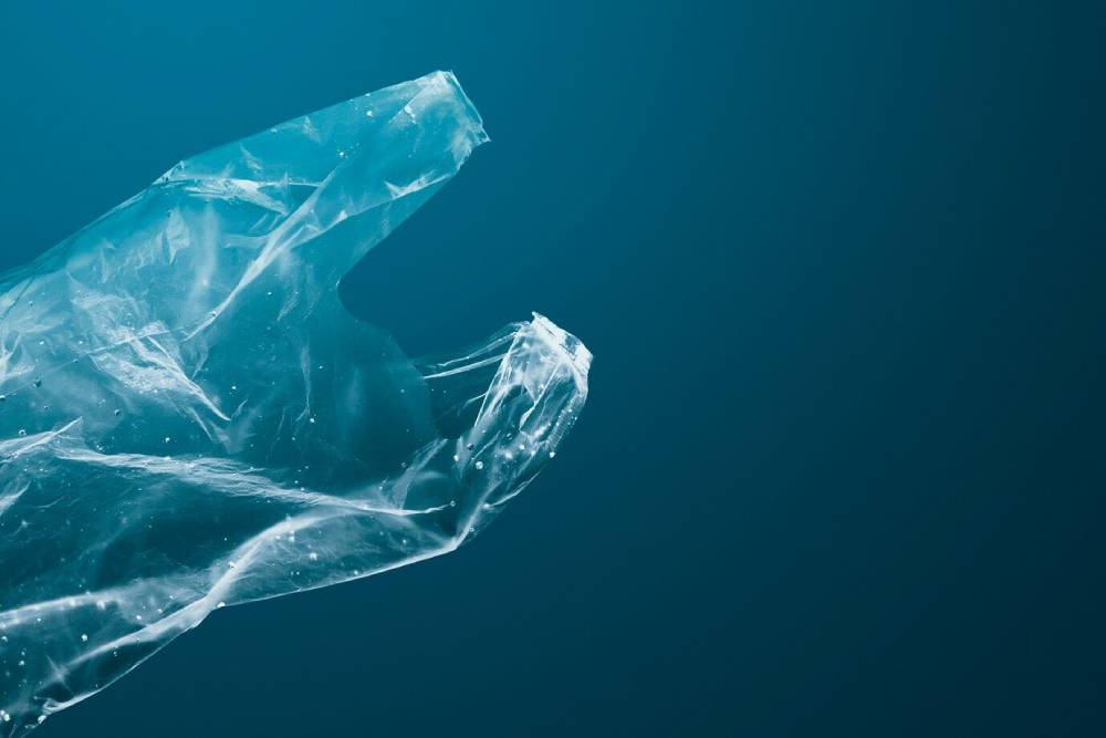 A translucent plastic bag floats gracefully against a dark blue background, highlighting the issue of plastic pollution.